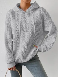 Close-up view of the grey cable knit textured hoodie featuring a drawstring hooded design.