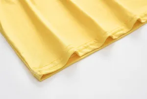 Close-up detail of yellow dress hem with fine stitching, high quality fabric texture.