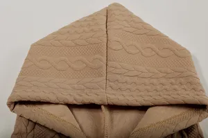 Detailed view of women's beige hooded sweatshirt featuring textured jacquard cable knit pattern.