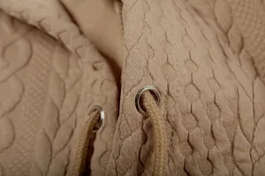 Detailed view of women's casual beige jacquard hoodie fabric with soft drawstring.