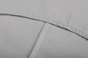 Grijze katoen linnen kledingstof detail close-up met fijne stiksels en nette afwerking.