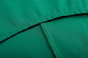 Detailfoto van groene katoenen linnen kledingstof met nette stiksels en fijne afwerking.