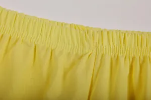 Detailopname van de gele casual broek elastische tailleband, fijne katoen linnen textuur.