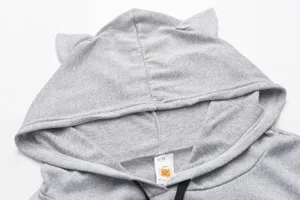 Close-up detail of gray knitted hoodie featuring cute cat ears and collar tag design.