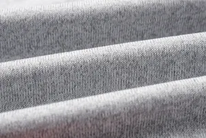 Close-up detail shot of soft grey heather knitted fabric showing comfortable texture and folds.