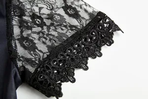 Gros plan détaillé de la dentelle florale noire sur la manche courte d'une élégante robe.