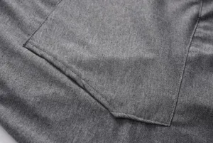 Detailed view of grey hooded sweatshirt fabric and pocket, showcasing fine stitching.