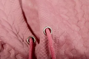 Close-up detail of women's pink jacquard hoodie with matching drawstring and metal eyelets.