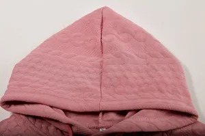 Pink jacquard hooded sweatshirt detail close-up showing textured knit and lace-up design.