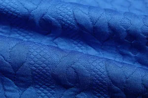 Close-up view of blue jacquard fabric showing fine woven monogram texture and details.