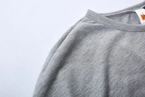 Detail view of grey long sleeve top shoulder, showing soft fabric and neat stitching.