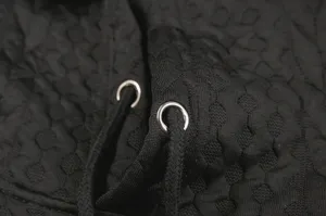 Close-up detail of black jacquard women's hoodie featuring metal eyelets and soft drawstring.