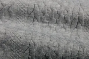 Grey jacquard sweatshirt fabric detail, soft knitted texture with classic geometric pattern.