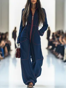 Women's blue denim jumpsuit featuring a V-neck, front zip, and stylish red contrast stitching.