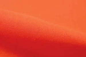 Close-up van oranje katoenen linnen stof met fijne textuur en een zacht aanvoelend oppervlak.