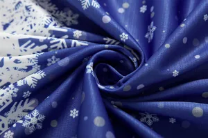 Detailed close-up of blue winter fabric featuring charming white snowflake and dot print patterns.
