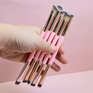 Vista detallada de brochas de maquillaje suaves con mangos rosas y virolas doradas.