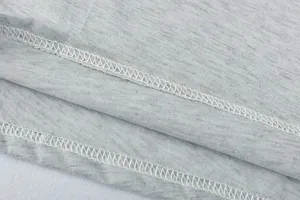 Detailed view of grey dress fabric and fine overlock stitching craftsmanship texture.