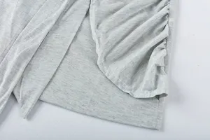 Close-up detail of light grey dress fabric showcasing stylish side ruching and irregular hem.