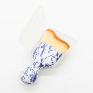 Curved contour makeup brush with wavy head and blue-white porcelain handle in case.