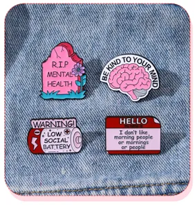 Detailaufnahme von vier Emaille-Anstecknadeln zum Thema psychische Gesundheit auf Jeans.