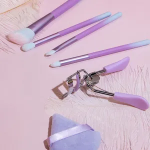 Close-up details of gradient purple makeup brush set and beauty tools on pink aesthetic background.