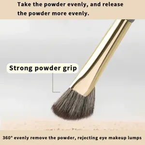 Detail shot of golden eye makeup brush with soft bristles for precise eyeshadow application.