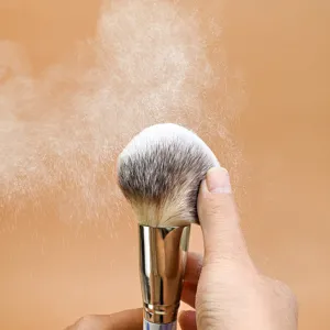 Close-up detail of fluffy makeup brush with soft bristles and dramatic powder effect.