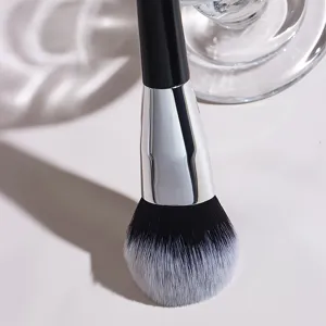 Nahaufnahme eines grossen Make-up-Pinsels mit weichen schwarz-weissen Borsten und Silber.