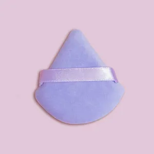 Close-up detail of soft purple triangle velvet makeup powder puff for flawless baking.