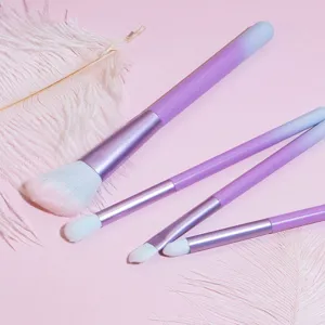 Detailed view of purple gradient makeup brushes set with soft white bristles on pink.