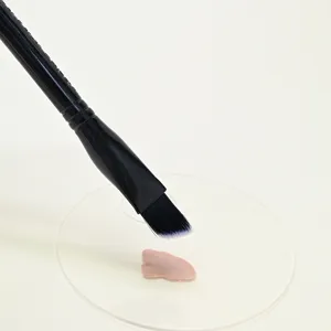 Λεπτομέρεια λοξού πινέλου concealer με απαλές τρίχες και foundation σε διαφανή παλέτα.
