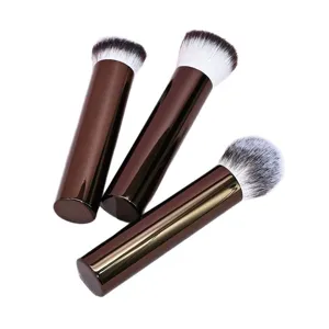 Set di tre pennelli da trucco portatili con manici marroni e setole bianche morbide.