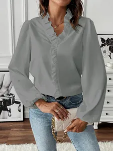 Close-up detail showcasing the elegant grey long sleeve ruffle V-neck shirt in interior room.