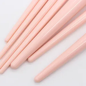 Close-up of pink makeup brush handles, showing smooth glossy finish and soft bristles detail.