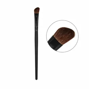 Primer plano de brocha de maquillaje biselada con mango negro y cerdas marrones suaves.