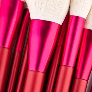 Macro detail shot of professional makeup brush set featuring soft white bristles and red metal handles.
