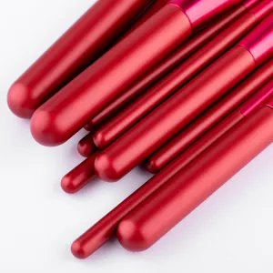 Close-up of professional red makeup brushes with smooth matte handles and metallic pink ferrules.