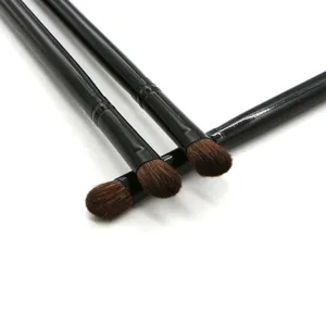 Vista detallada de brochas de maquillaje negras de mango largo con cerdas marrones para ojos.