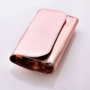 Detail view of a metallic pink cosmetic brush bag containing sparkling diamond makeup tools.
