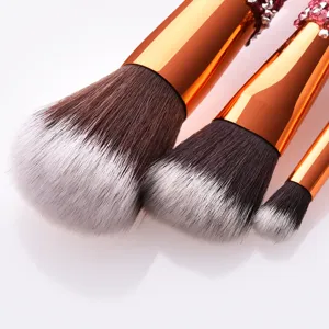 Detailed view of luxury rhinestone makeup brush set featuring soft gradient bristles and gold metal.