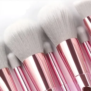 Nahaufnahme von professionellen Make-up-Pinseln mit weissen Borsten und rosa Metallgriffen.