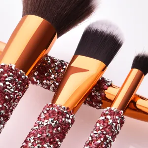 Detailed closeup of rhinestone makeup brushes with rose gold ferrule and sparkling crystals.
