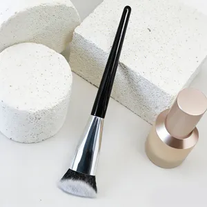 Gros plan d'un pinceau de maquillage noir avec des poils synthétiques biseautés.