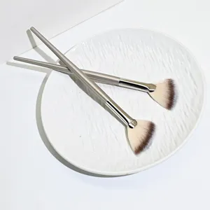 Close-up detail of soft synthetic fiber fan highlighter brush for precise eye makeup application.