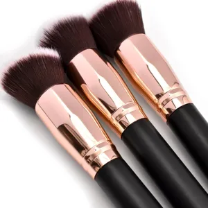 Primer plano detalle de brochas de maquillaje suaves con virolas oro rosa y mangos negros.