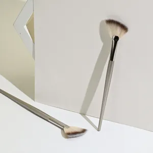 Professional fan makeup brush for facial highlighting and precise powder application in soft tones.