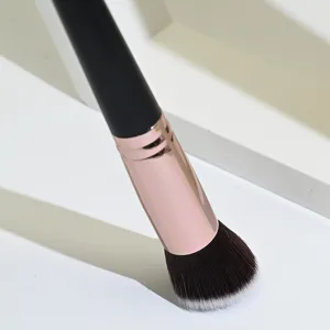 Primer plano detallado de brocha de maquillaje angular profesional con cerdas suaves y virola dorada.