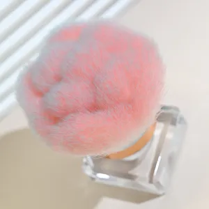 Close-up of fluffy pink makeup brush with clear square base, soft bristles detail.
