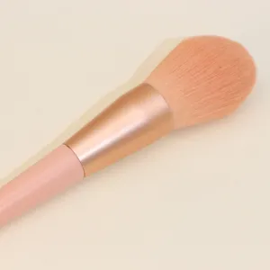 Weicher rosafarbener Make-up-Pinsel im Detail, flauschiger Puderpinsel mit goldenem Griff.